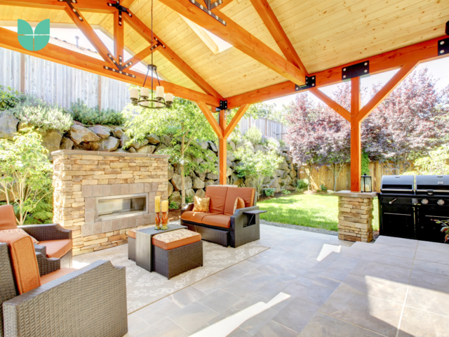 A outdoor living space covered, with a fire place, garden furniture and a barbecue. 